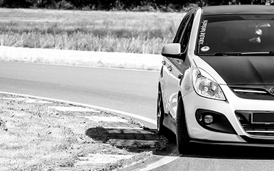 Nahaufnahme eines Hyundai i20, die Frontpartie und ein Teil der Seite sind im Schwarz-Weiß-Bild sichtbar, auf dem Asphalt einer Rennstrecke. Der Fokus liegt auf der Fahrzeugfront. Fotografie Michael Schalansky.